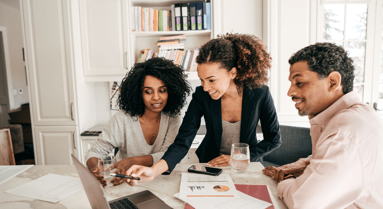 Three people reviewing housing market numbers together at a laptop