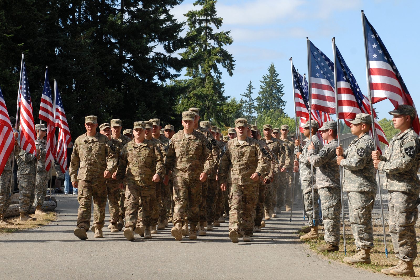 Soldiers of the 4th Stryker Brigade marching between rows of American flags at a welcome home ceremony at JBLM