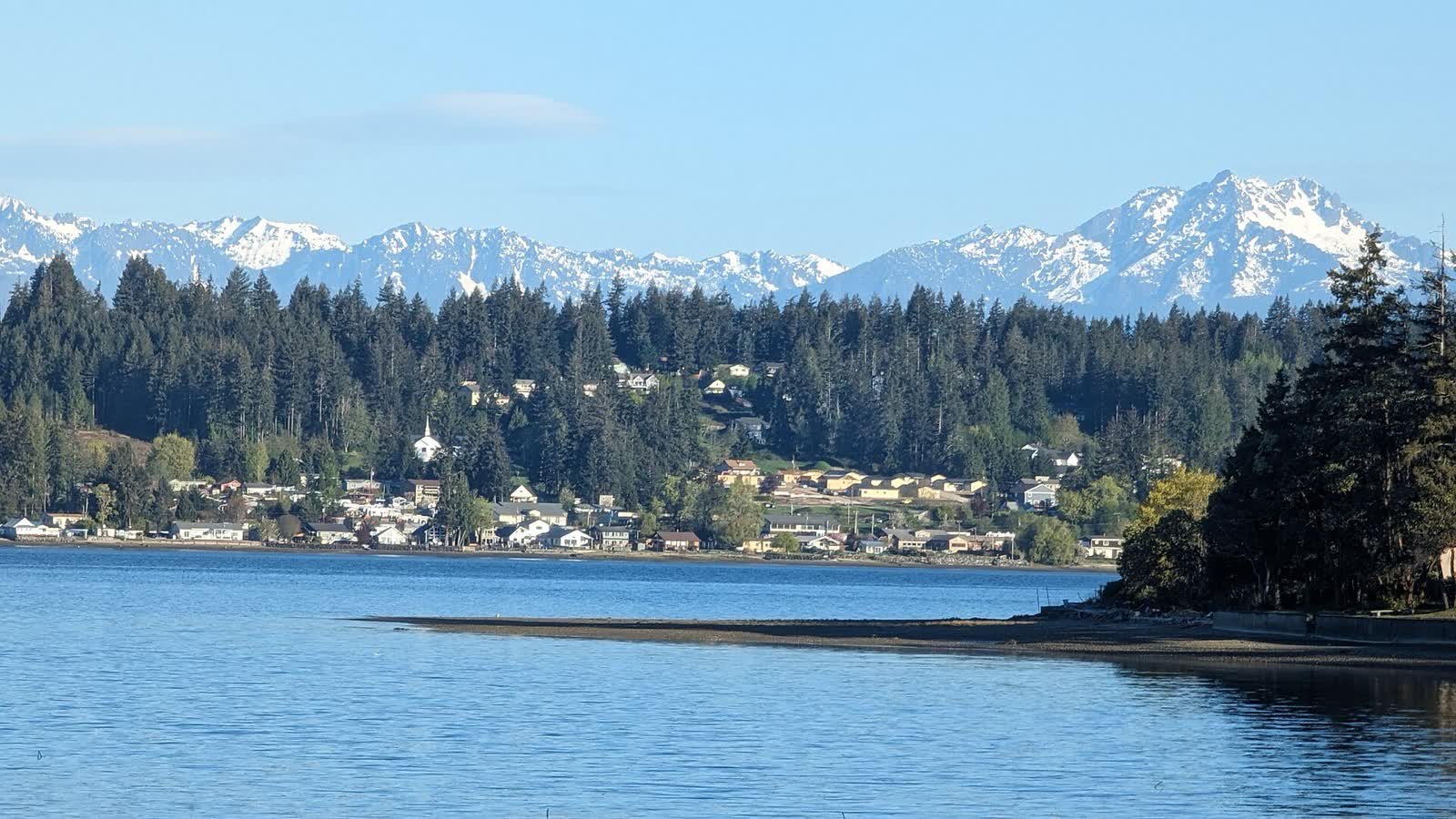 Allyn's shoreline homes seen across North Bay on Case Inlet, with the snow-capped Olympic Mountains on the horizon