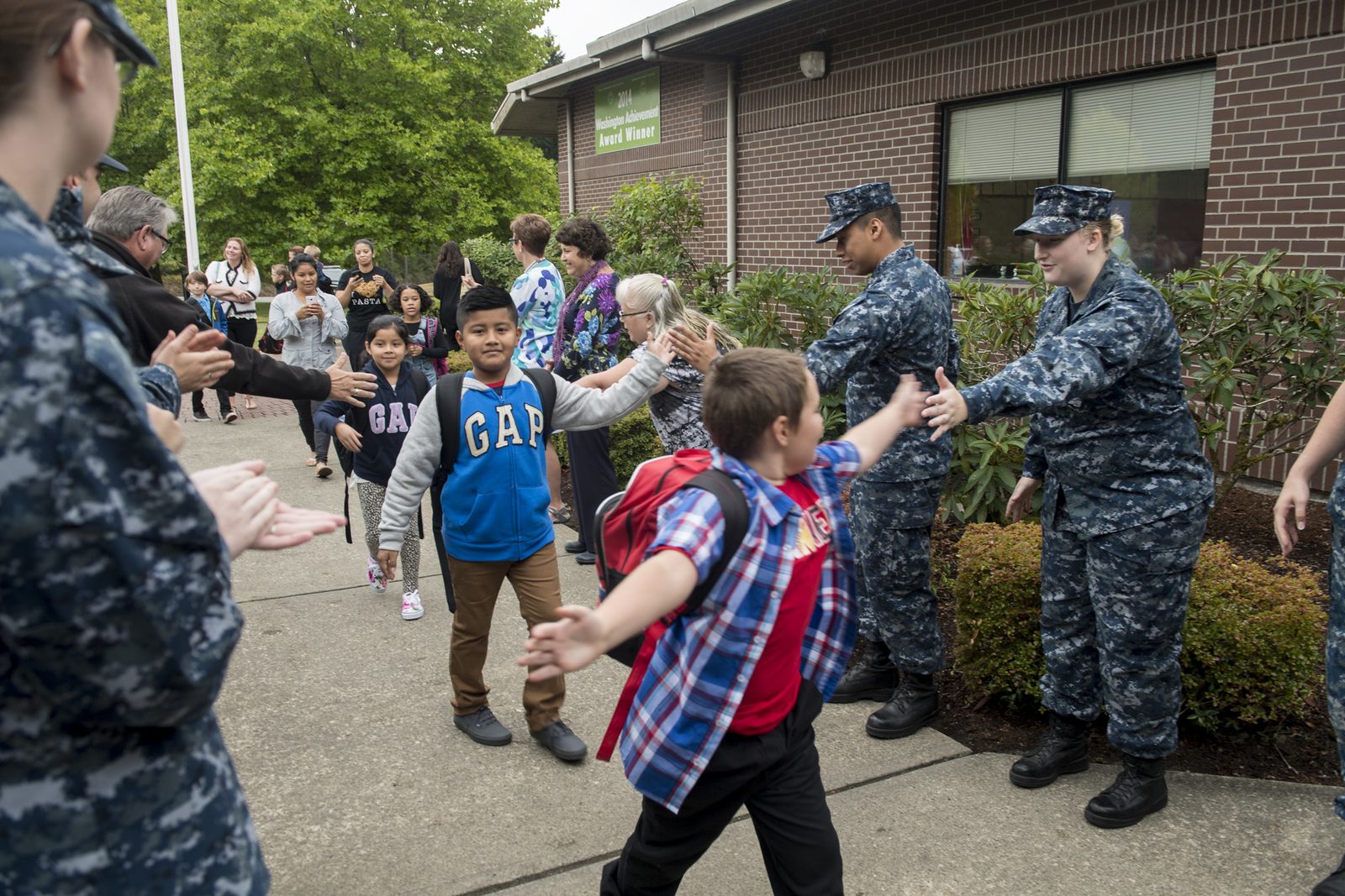 Naval Base Kitsap sailors high-five students in a victory tunnel at Sand Hill Elementary School in Belfair