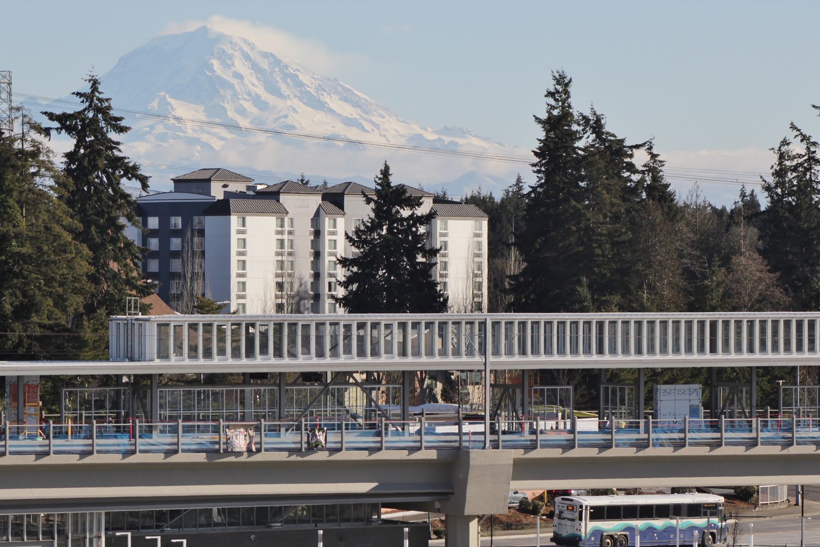 Mount Rainier rising behind the elevated platform of Federal Way Downtown Station, with a Sound Transit bus passing below
