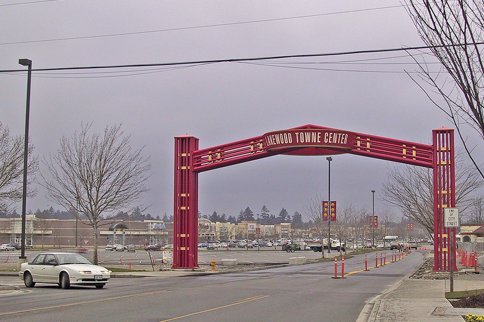 The red gateway arch at the entrance to Lakewood Towne Center in Lakewood, Washington, with the shopping center behind it