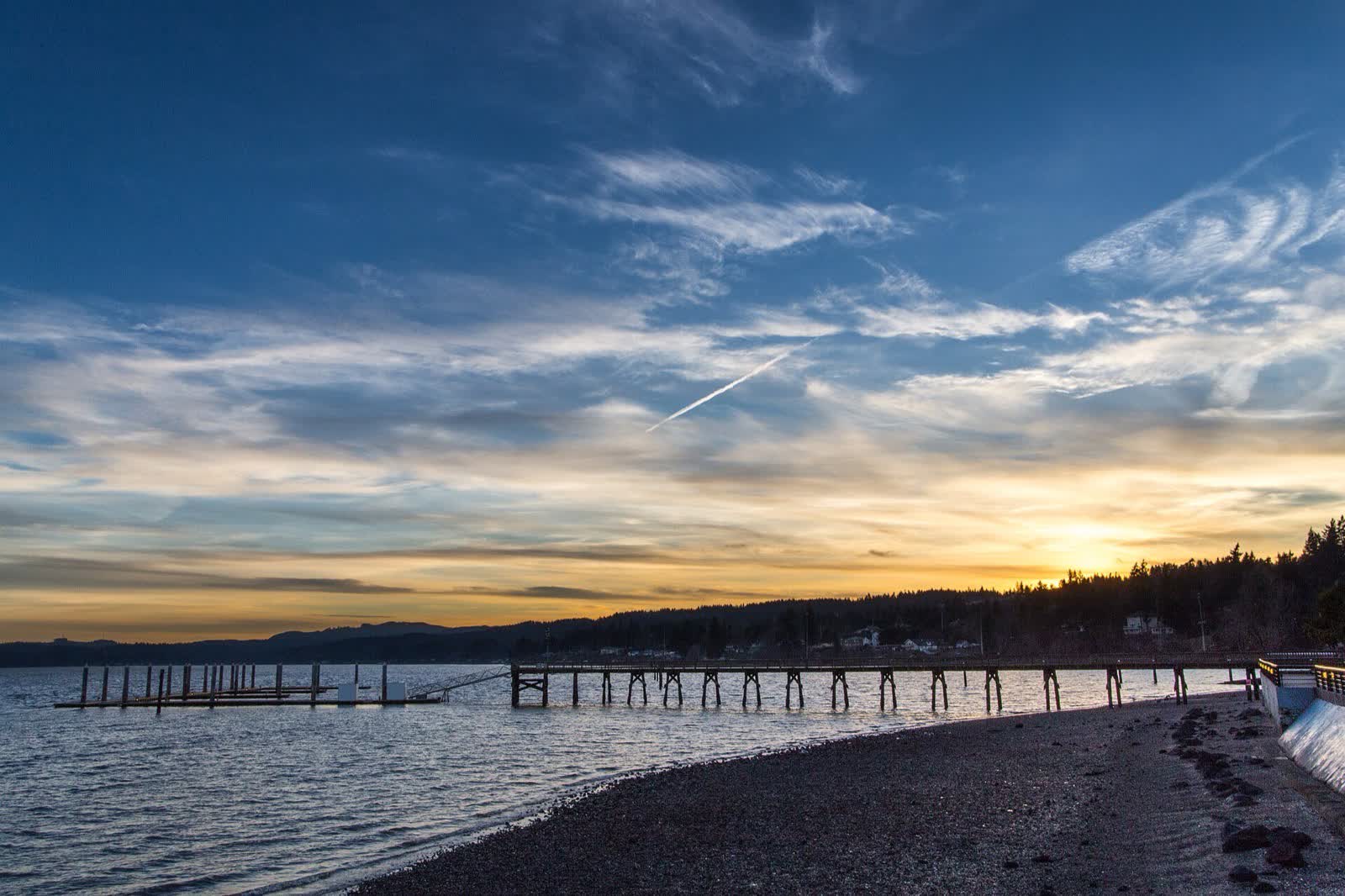 The pier at Silverdale's Waterfront Park reaching into Dyes Inlet at sunset, with Old Town's homes along the shore